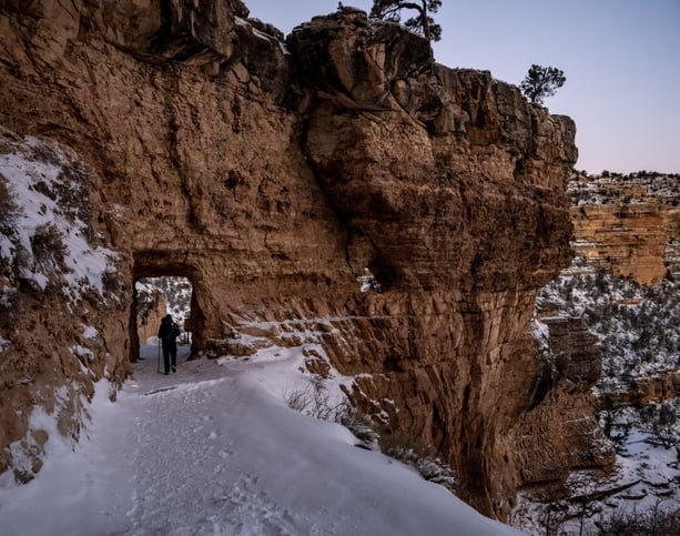 Hiker Passing Through Snow Covered Tunnel Along Bright Angel Trail in Grand Canyon National Park